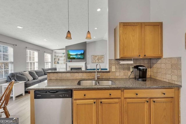 kitchen featuring vaulted ceiling, pendant lighting, sink, stainless steel dishwasher, and a textured ceiling