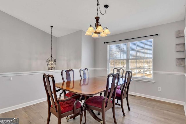 dining area with vaulted ceiling, a chandelier, and light hardwood / wood-style flooring