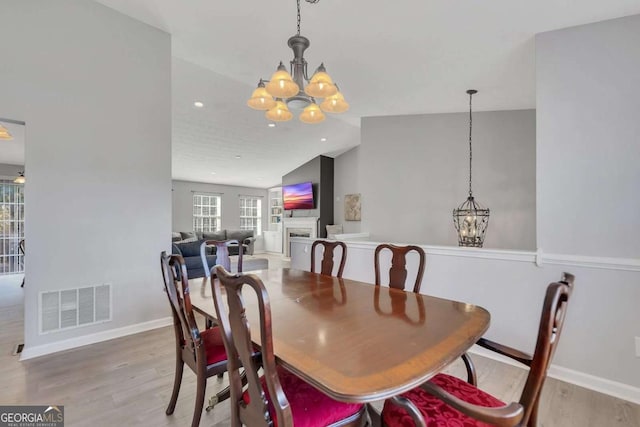 dining room with lofted ceiling, a chandelier, and light hardwood / wood-style floors