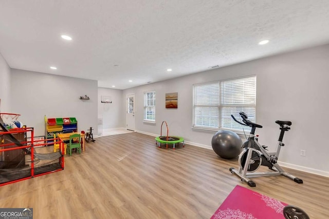 exercise area with light hardwood / wood-style flooring and a textured ceiling