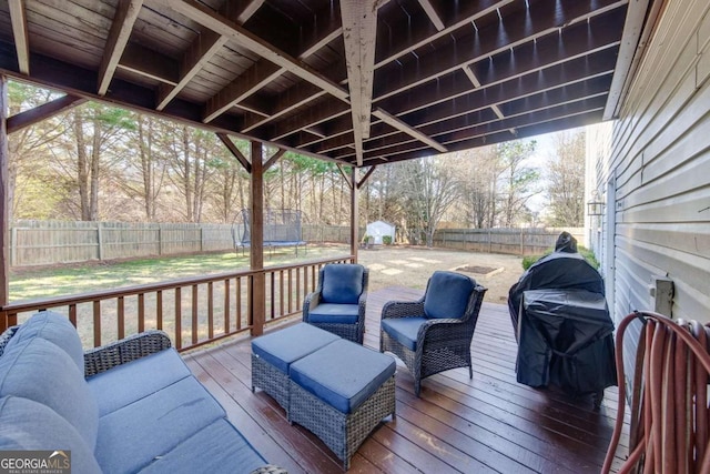 wooden deck with an outdoor living space and a trampoline