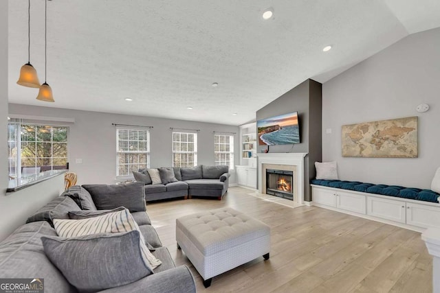 living room with lofted ceiling, a textured ceiling, and light wood-type flooring