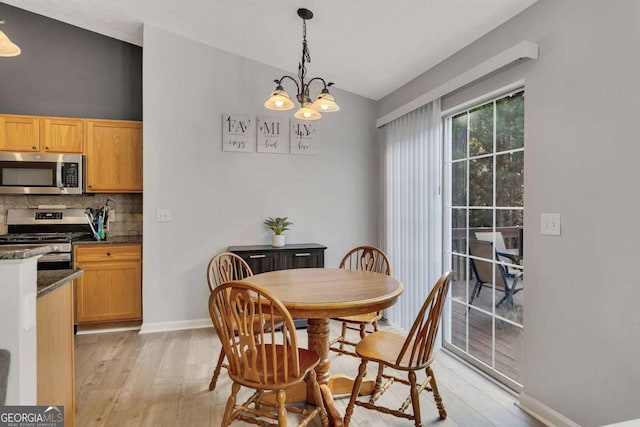 dining room with lofted ceiling, a notable chandelier, and light hardwood / wood-style floors