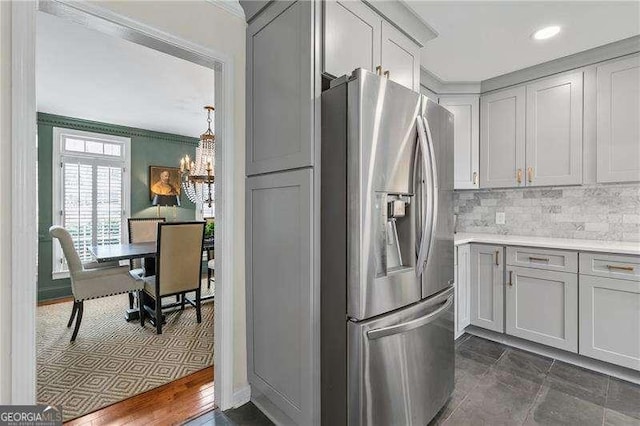 kitchen featuring gray cabinets, stainless steel fridge with ice dispenser, decorative backsplash, and a notable chandelier