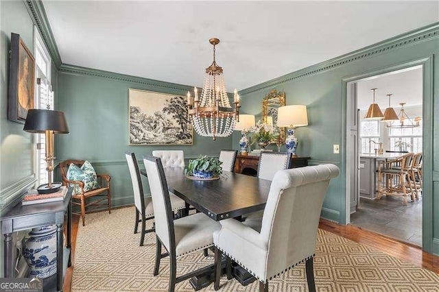 dining area featuring an inviting chandelier, ornamental molding, and light hardwood / wood-style floors