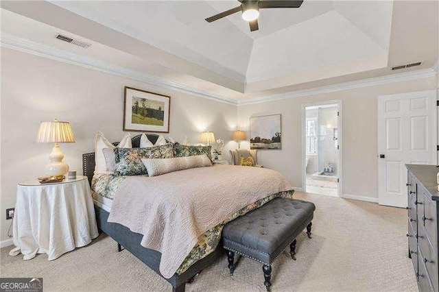 carpeted bedroom with a tray ceiling, ensuite bath, ornamental molding, and ceiling fan