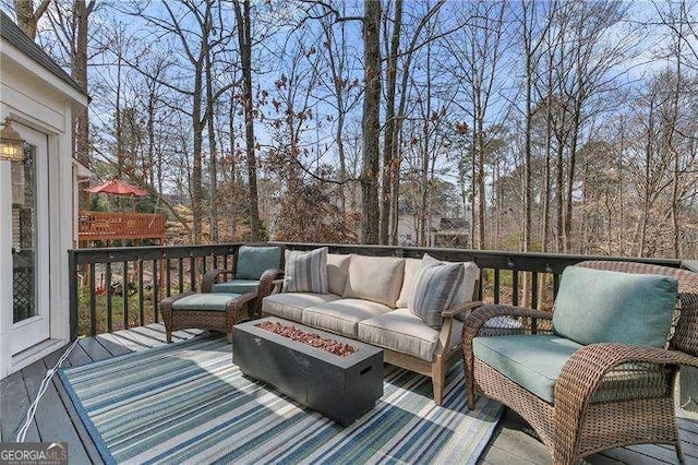 wooden deck featuring an outdoor living space with a fire pit