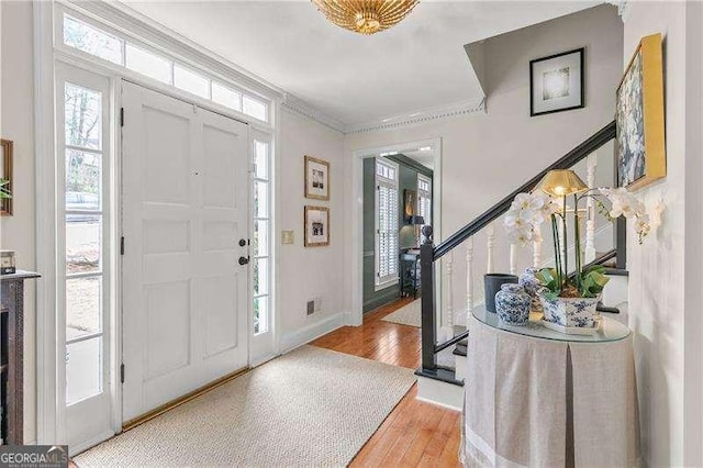 entrance foyer with ornamental molding and light hardwood / wood-style floors