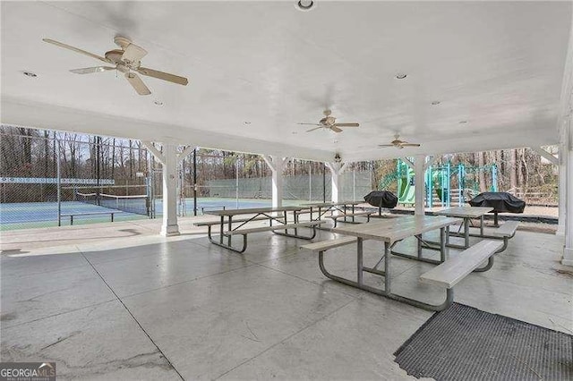 view of patio / terrace featuring ceiling fan, a playground, and tennis court