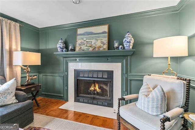 sitting room with hardwood / wood-style flooring and ornamental molding