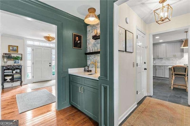 bathroom featuring an inviting chandelier, hardwood / wood-style floors, decorative backsplash, and sink