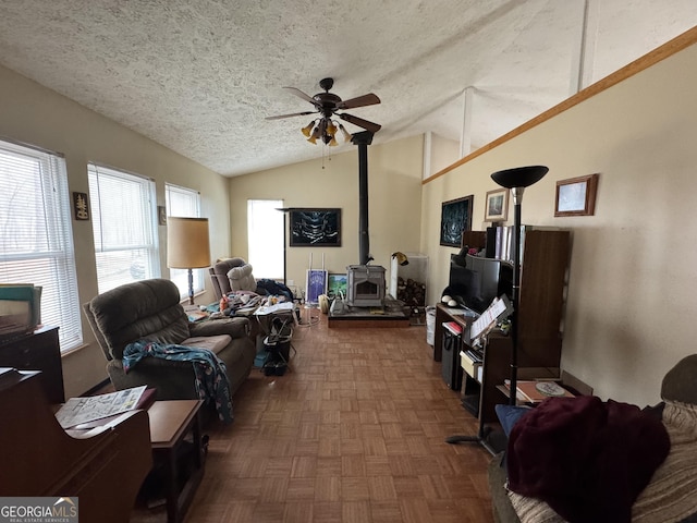 living room featuring dark parquet flooring, vaulted ceiling, a textured ceiling, a wood stove, and ceiling fan