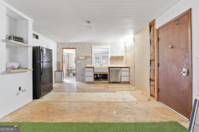 kitchen featuring sink, light hardwood / wood-style flooring, stainless steel dishwasher, and black fridge