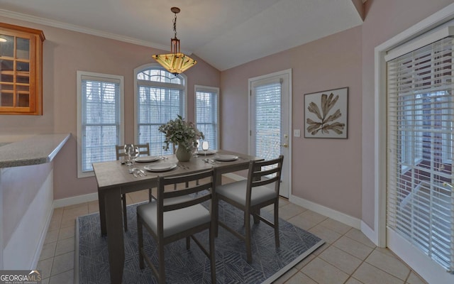 dining space with lofted ceiling, crown molding, baseboards, and light tile patterned floors