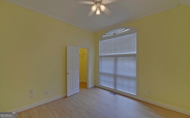 empty room with light wood finished floors, visible vents, ornamental molding, and baseboards