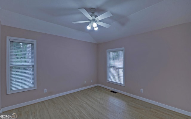 spare room with light wood-type flooring, baseboards, visible vents, and vaulted ceiling