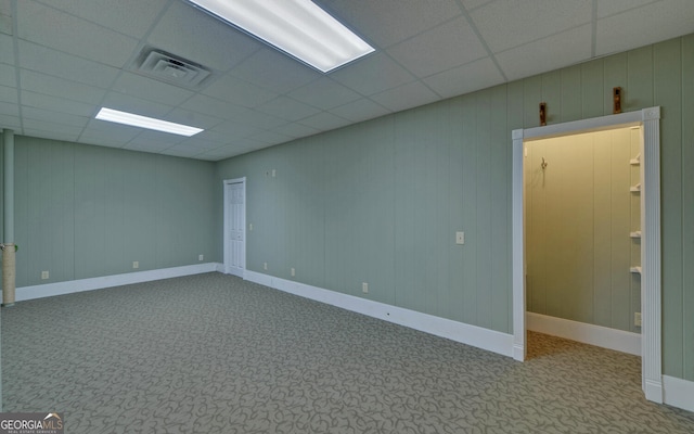 empty room with a drop ceiling, carpet, visible vents, and baseboards