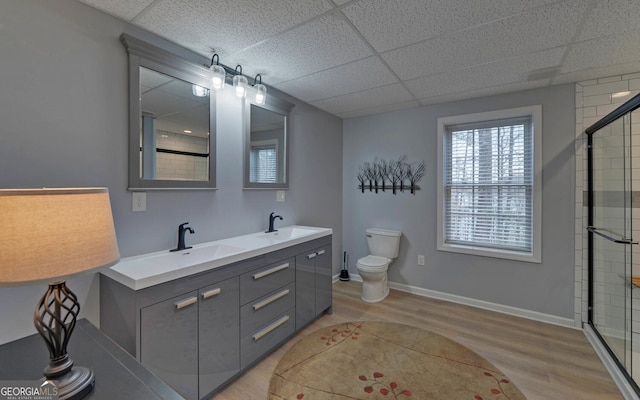 full bathroom featuring a drop ceiling, a sink, toilet, and wood finished floors