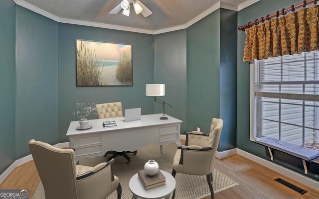 office area with baseboards, light wood finished floors, visible vents, and crown molding