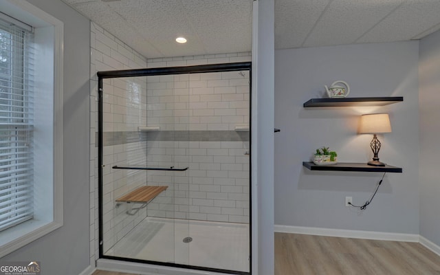 bathroom featuring a shower stall, a healthy amount of sunlight, wood finished floors, and baseboards