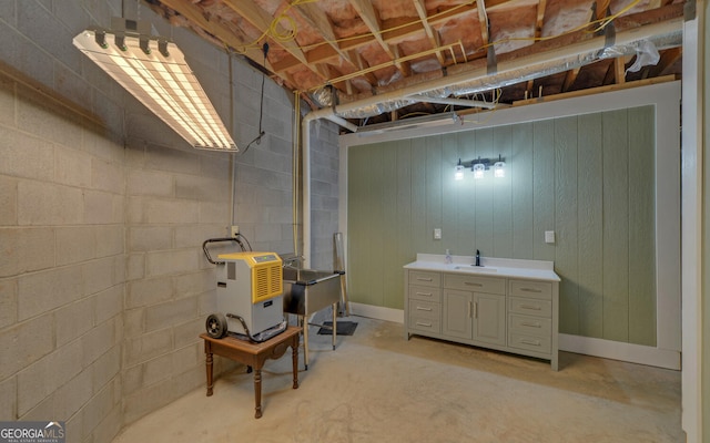 unfinished basement featuring concrete block wall and a sink