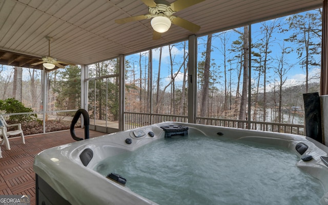 sunroom / solarium with a wooded view and a hot tub