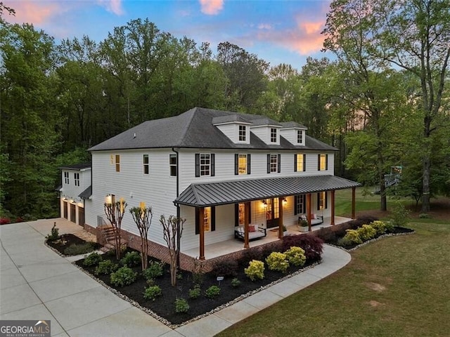 back house at dusk with a yard, a garage, and a porch