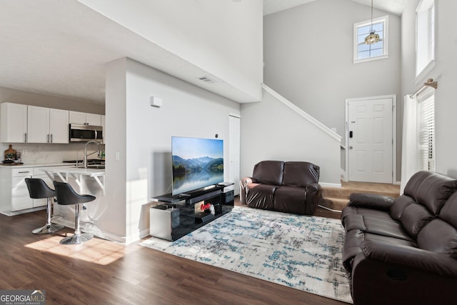 living room with sink, wood-type flooring, and a high ceiling