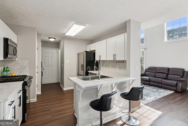 kitchen featuring sink, white cabinetry, a kitchen breakfast bar, kitchen peninsula, and stainless steel appliances