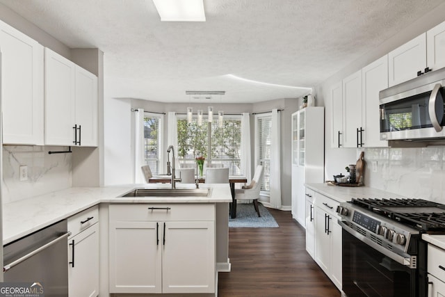 kitchen featuring dark wood-type flooring, sink, white cabinetry, decorative light fixtures, and stainless steel appliances