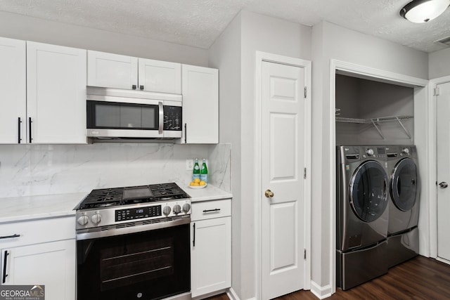 kitchen with appliances with stainless steel finishes, white cabinetry, decorative backsplash, washing machine and clothes dryer, and dark wood-type flooring