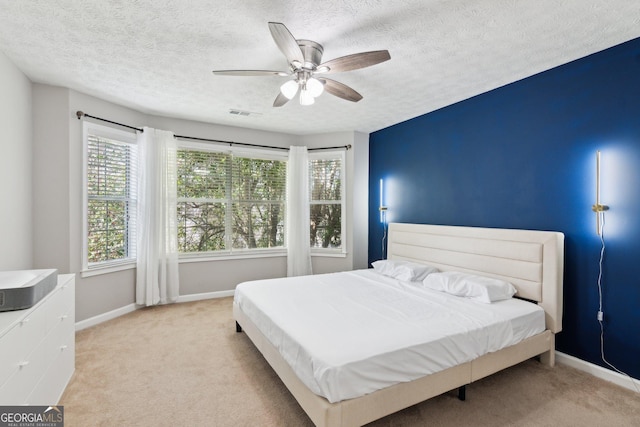 carpeted bedroom with ceiling fan and a textured ceiling