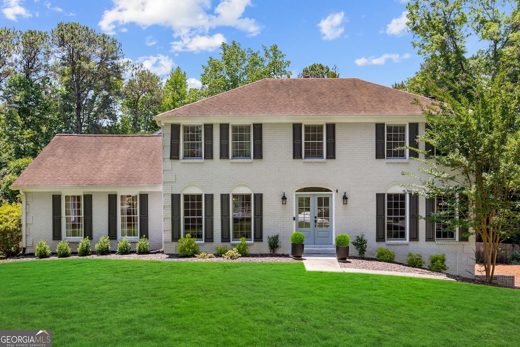 colonial inspired home featuring a front yard and french doors