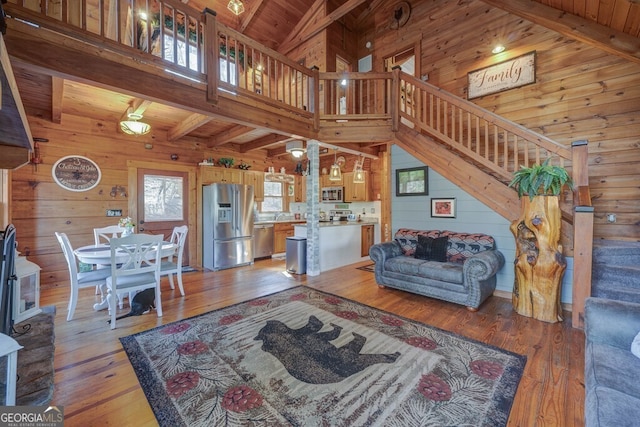 living room featuring beam ceiling, wood-type flooring, wood ceiling, and wooden walls