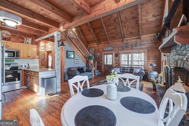 dining area featuring wood ceiling, wooden walls, dark hardwood / wood-style floors, and a stone fireplace