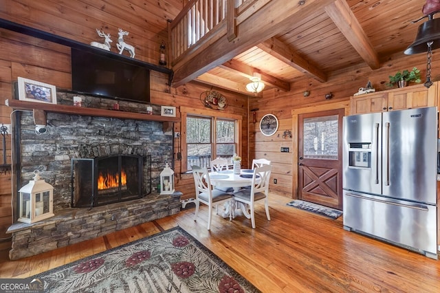 dining area featuring wood ceiling, wooden walls, beamed ceiling, and light wood-type flooring