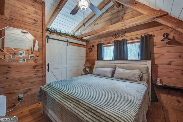 bedroom with hardwood / wood-style flooring, lofted ceiling with beams, a barn door, and wood walls