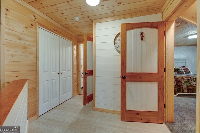 hallway featuring wood ceiling, light hardwood / wood-style flooring, and wood walls