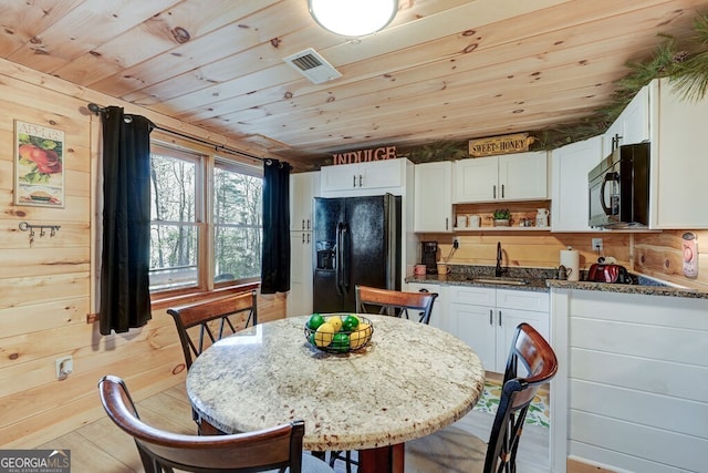 kitchen with white cabinetry, sink, black appliances, and dark stone counters