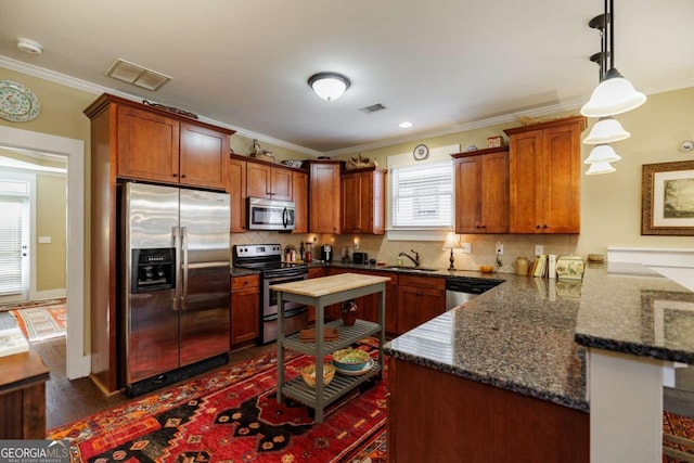 kitchen with decorative light fixtures, sink, kitchen peninsula, stainless steel appliances, and crown molding