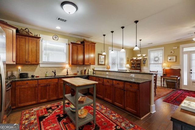 kitchen with dark hardwood / wood-style floors, tasteful backsplash, sink, dark stone counters, and hanging light fixtures