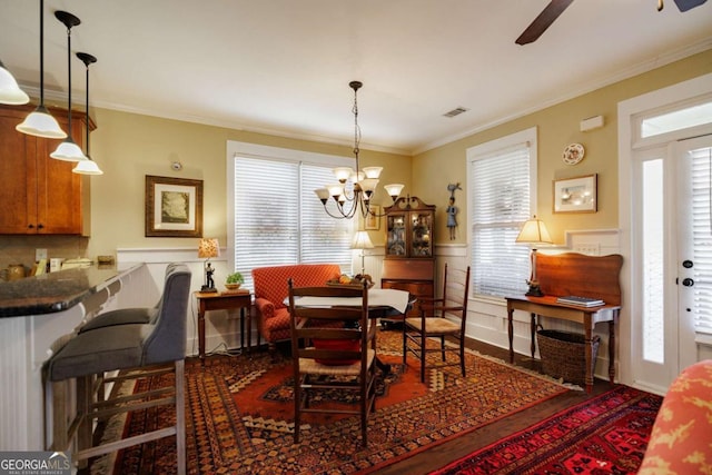 dining area featuring ceiling fan with notable chandelier, dark wood-type flooring, ornamental molding, and a healthy amount of sunlight