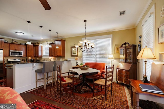 dining space featuring ornamental molding, dark hardwood / wood-style flooring, and an inviting chandelier