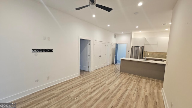 kitchen featuring white cabinetry, stainless steel refrigerator, ceiling fan, light hardwood / wood-style floors, and decorative backsplash