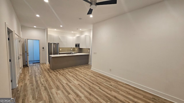 kitchen featuring sink, appliances with stainless steel finishes, light hardwood / wood-style floors, white cabinets, and decorative backsplash