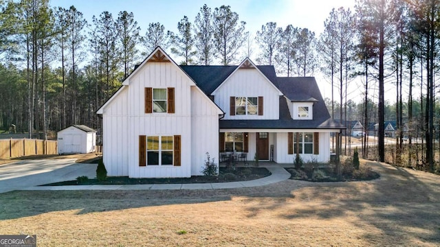 modern inspired farmhouse featuring a storage unit, covered porch, and a front yard