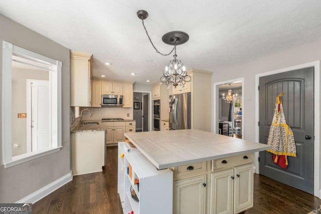 kitchen with cream cabinets, stainless steel appliances, sink, and a kitchen island