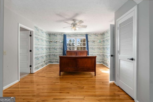 home office featuring ceiling fan, light hardwood / wood-style flooring, and a textured ceiling