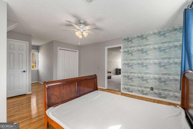 bedroom featuring ceiling fan, a textured ceiling, light wood-type flooring, and a closet