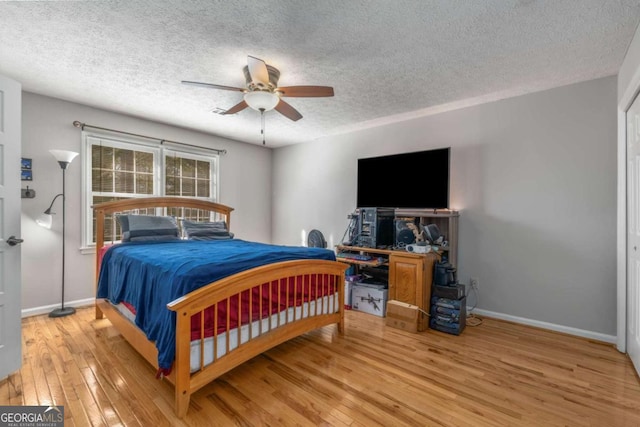 bedroom with hardwood / wood-style floors, a textured ceiling, and ceiling fan